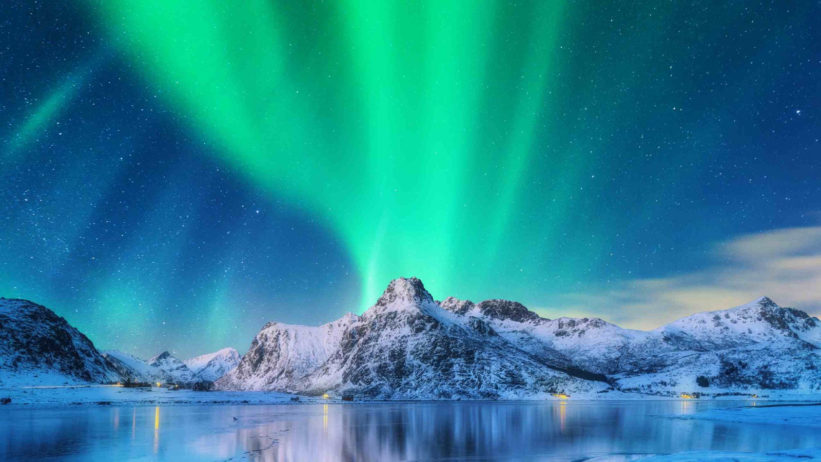 Green and violet aurora curtains over a snow-covered fjord in Tromsø, Norway, during the 2026–27 northern lights season
